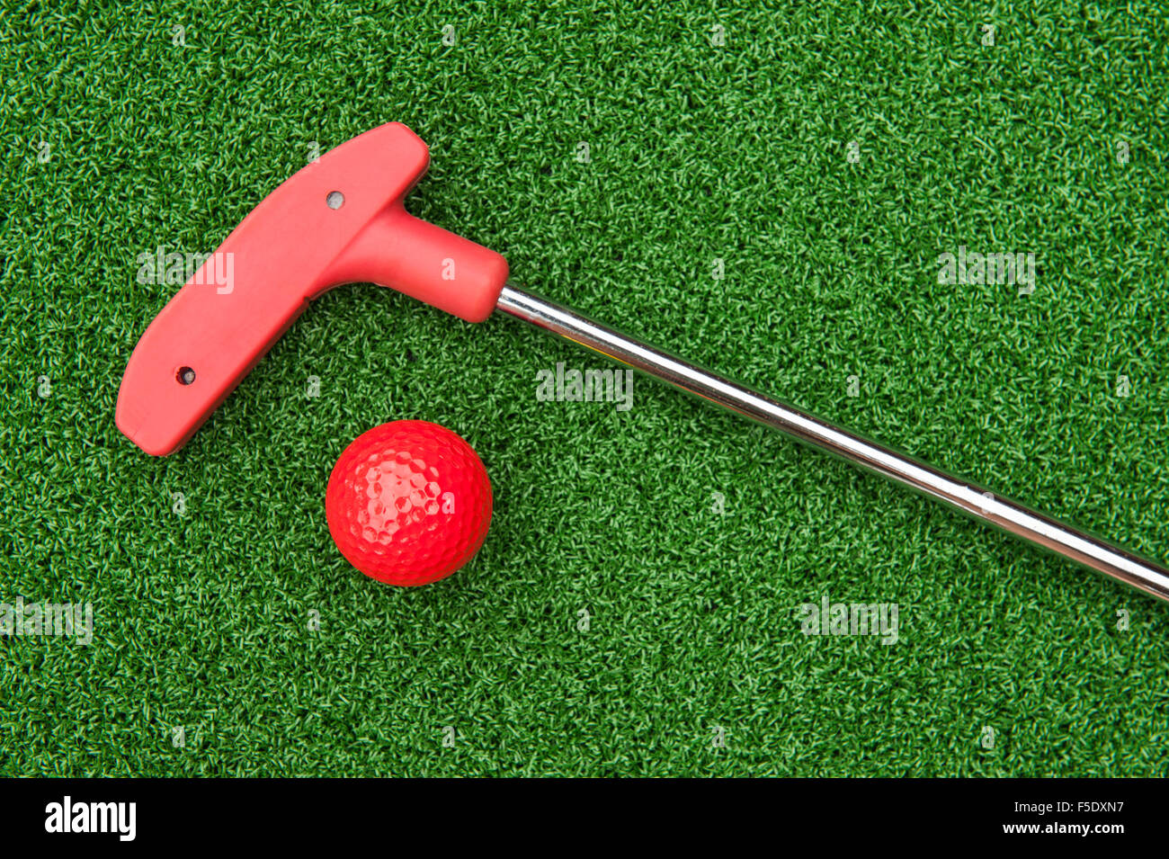 Red mini golf putter and ball laying on artificial turf Stock Photo