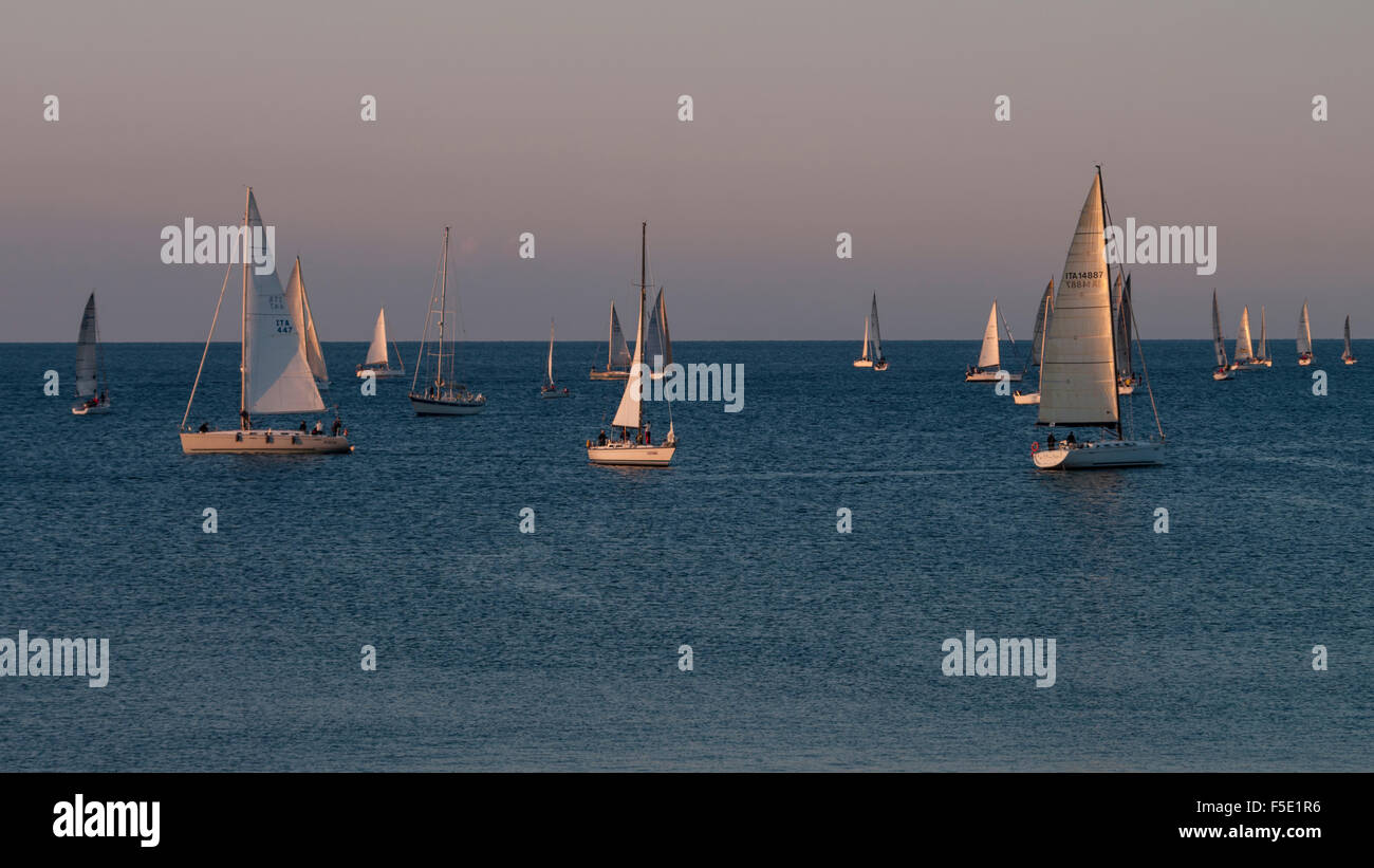Many small sail boats cruising the Mediterranean Sea early in the morning. Stock Photo