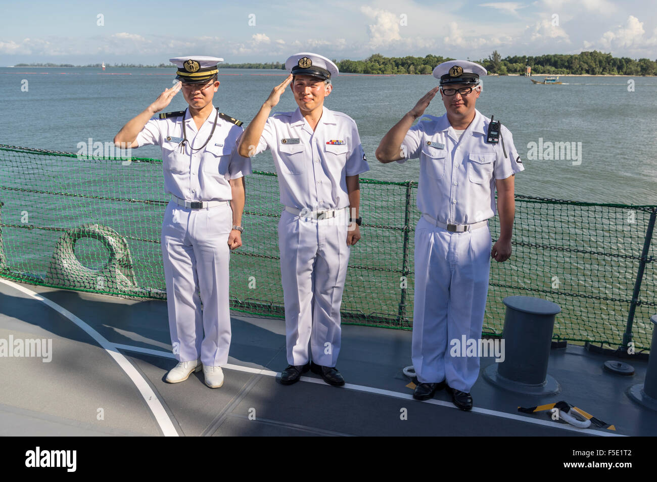 Group of three male sailors of the Japanese navy (Japan Maritime Self-Defense Force) standing guard and saluting. Stock Photo