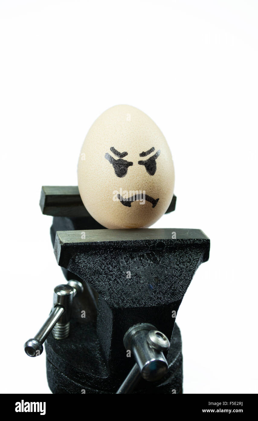 Egg with sad face painted on it on top of a vice, conceptual image about stress and health related problems, isolated on white Stock Photo