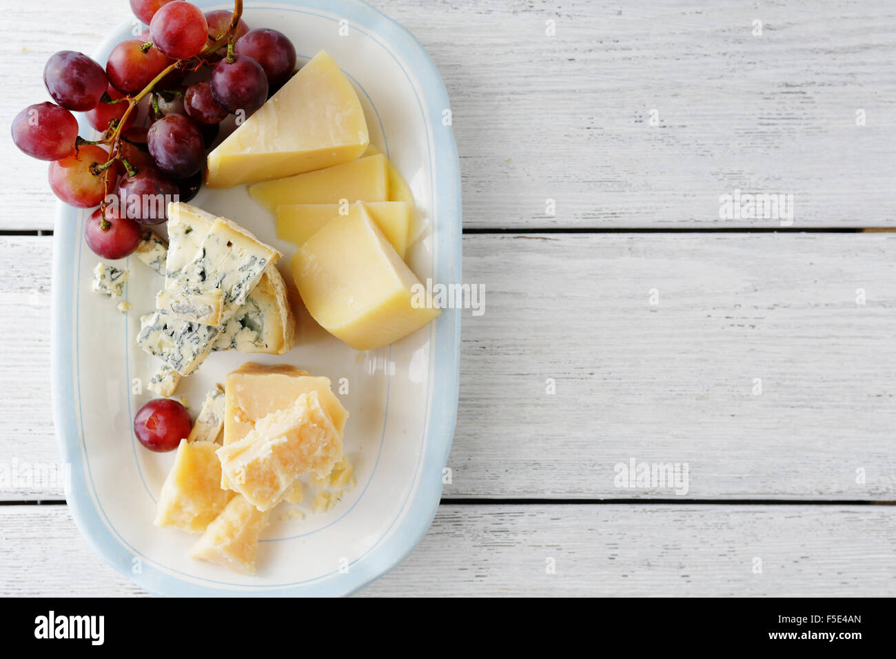 cheeses and red grapes on plate, planks food background Stock Photo Alamy