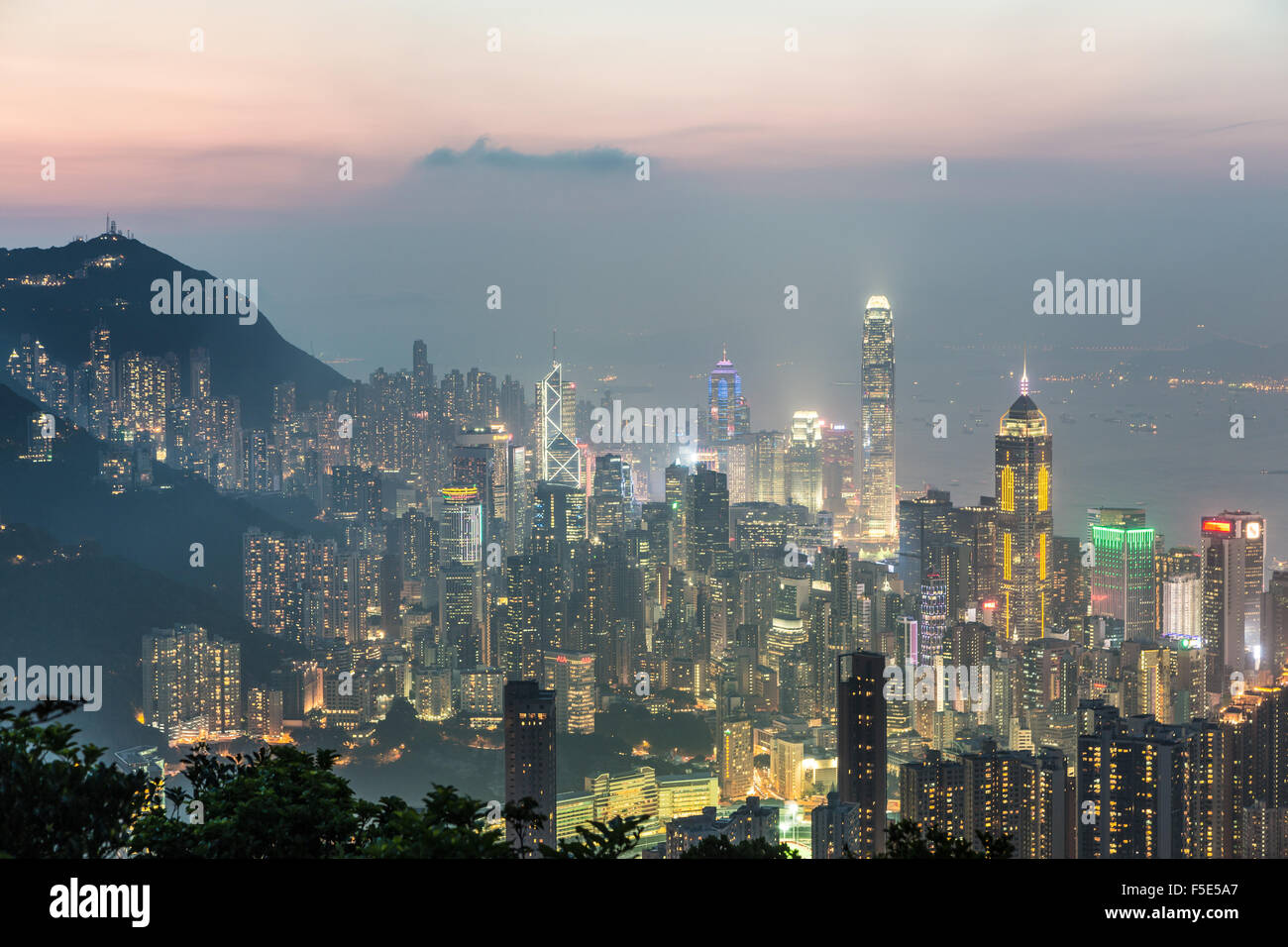 Hong Kong skyline shot after sunset from the top of a mountain in Hong Kong island. The view goes through the Victoria harbor un Stock Photo