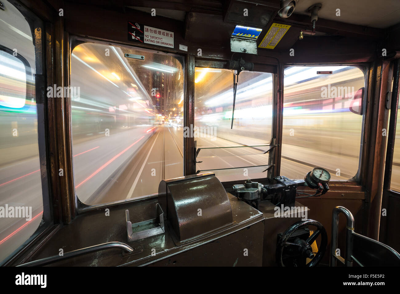 Inside a Tram car rushing through Hong Kong island streets at night. WIde angle and long exposure are used. Stock Photo