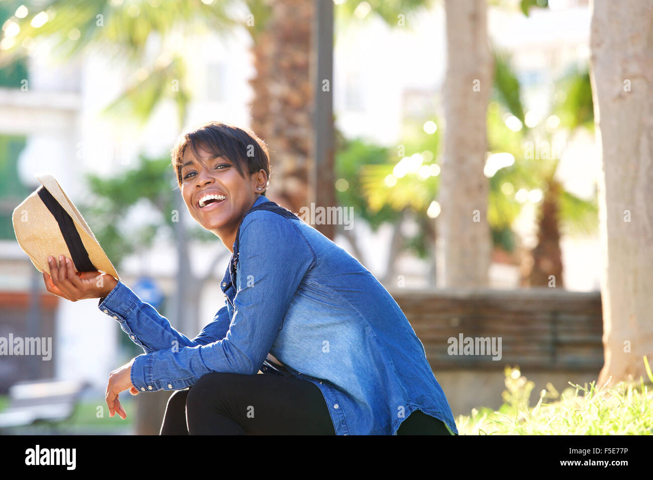 Profile portrait of a young black woman laughing outside with hat Stock ...