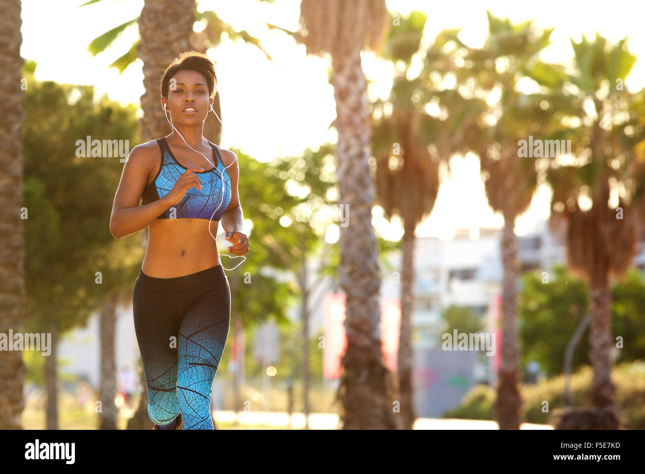 Runner woman running on beach with watch and sports bra top. Beautiful fit  female fitness model training and working out outside in summer at part of  healthy lifestyle Stock Photo