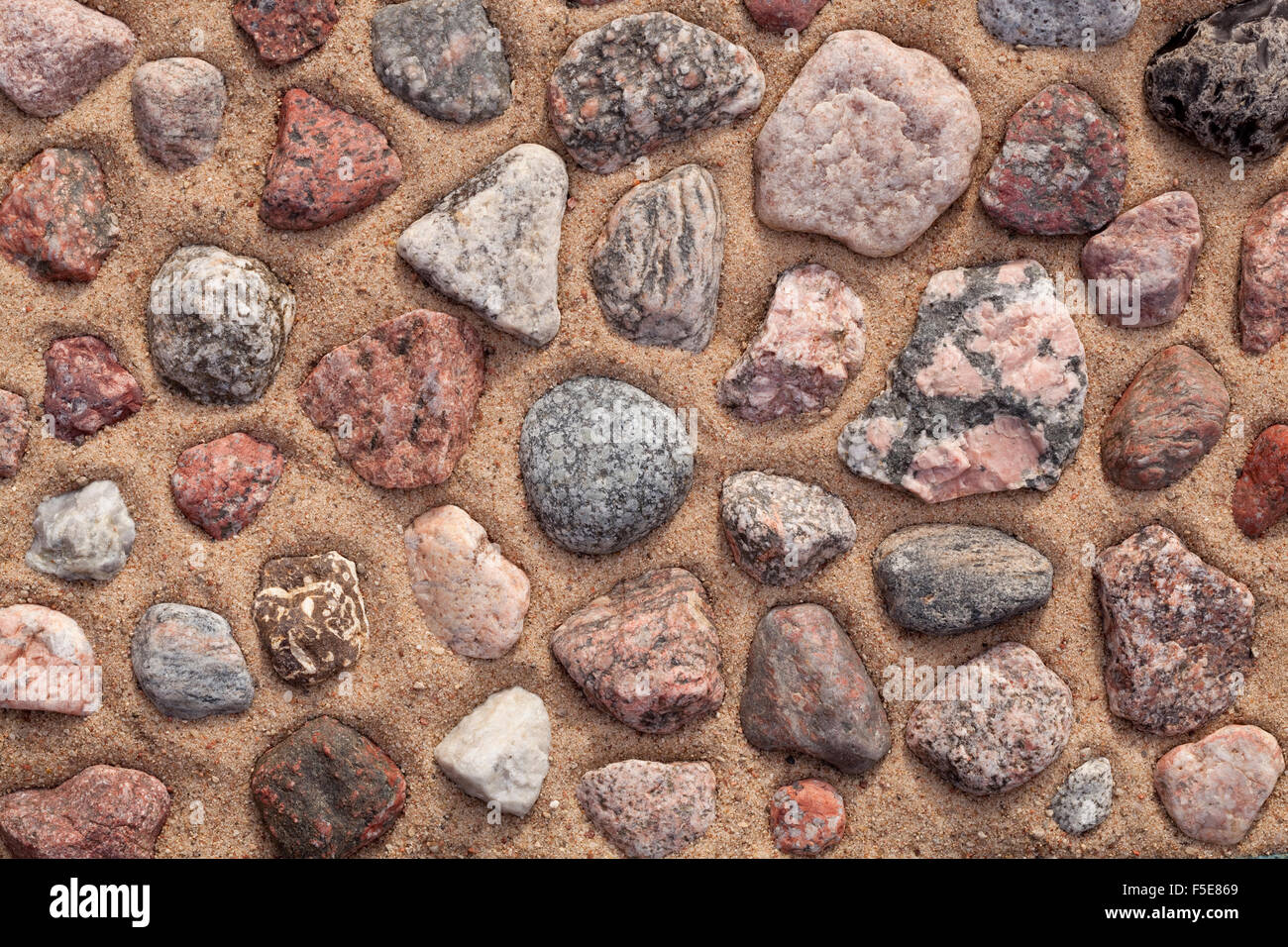 dry colourful stones arranged on sand as background Stock Photo