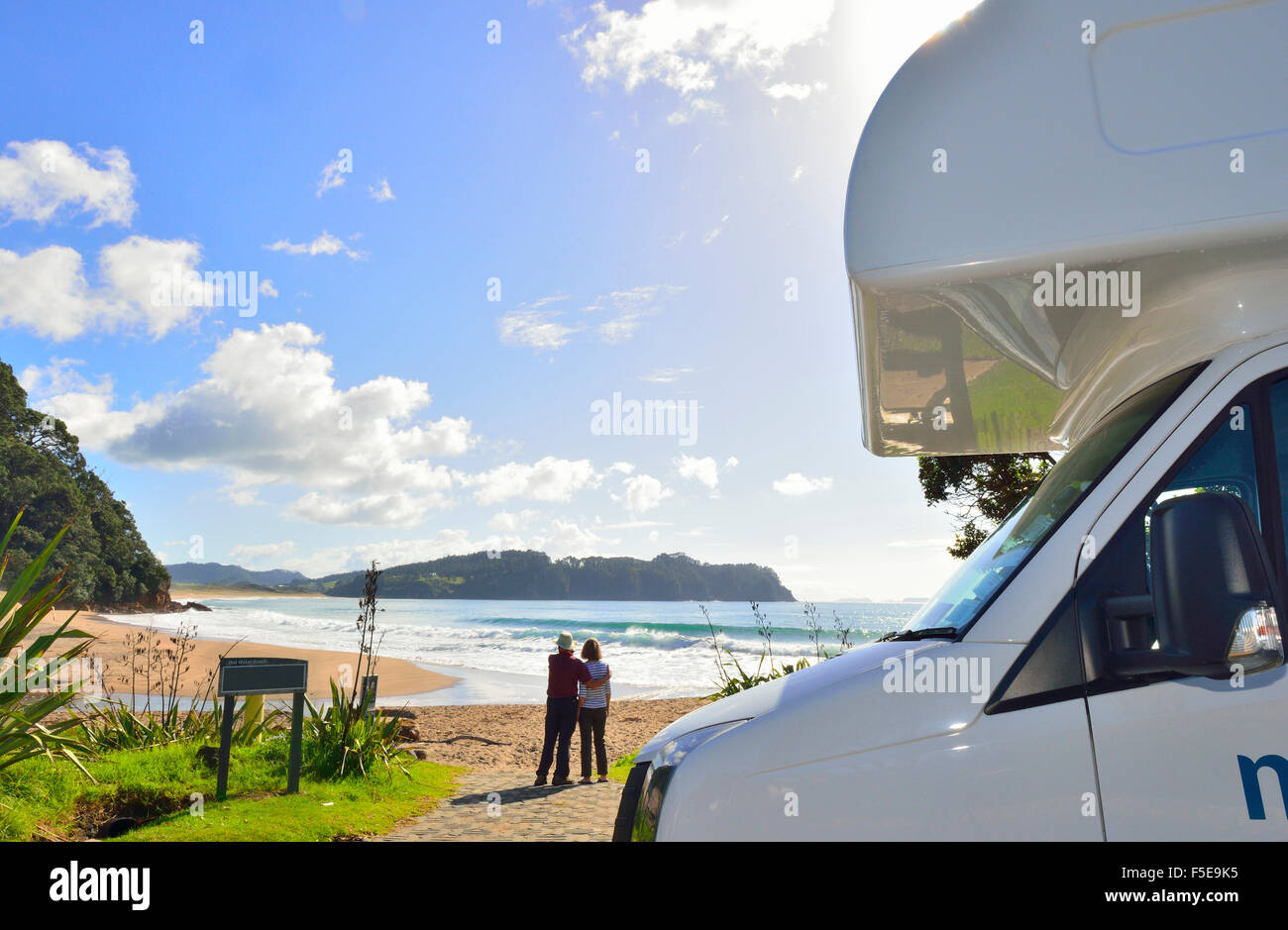 A man and woman in front of their  rented Maui motorhome looking at the view at Hot Water Beach on Coromandel peninsula, North Island, New Zealand Stock Photo