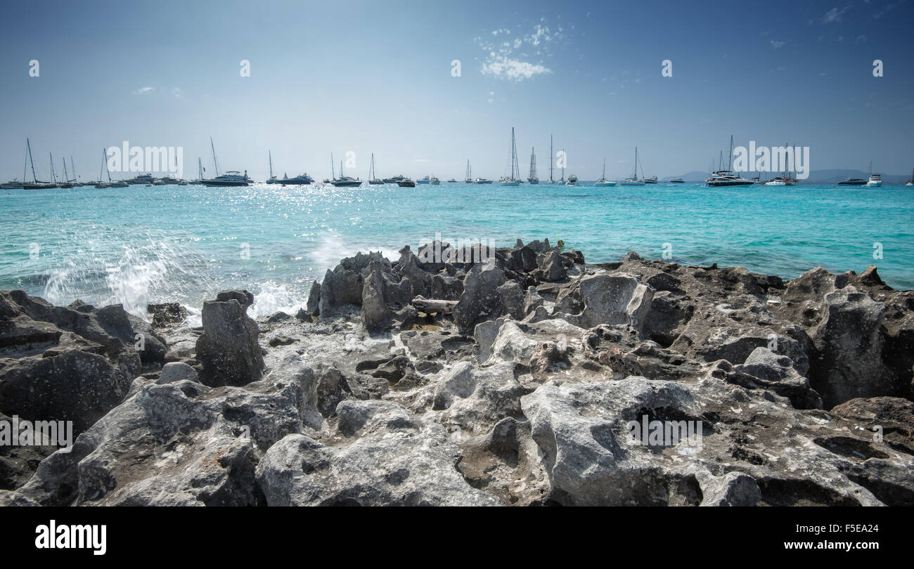 Jagged rocks with sailboats idling in the azure waters of Formentera, Balearic Islands, Spain, Mediterranean, Europe Stock Photo