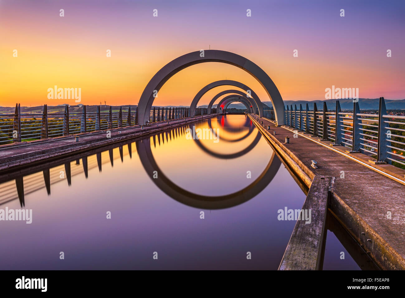 Falkirk Wheel at sunset. Falkirk Wheel is a rotating boat lift in Scotland and connects the Forth and Clyde Canal with the Union Stock Photo