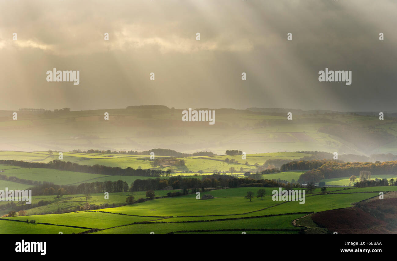 Sun illuminating fields in rural landscape in November, seen from Baslow Edge, Peak District, Derbyshire, England, UK Stock Photo