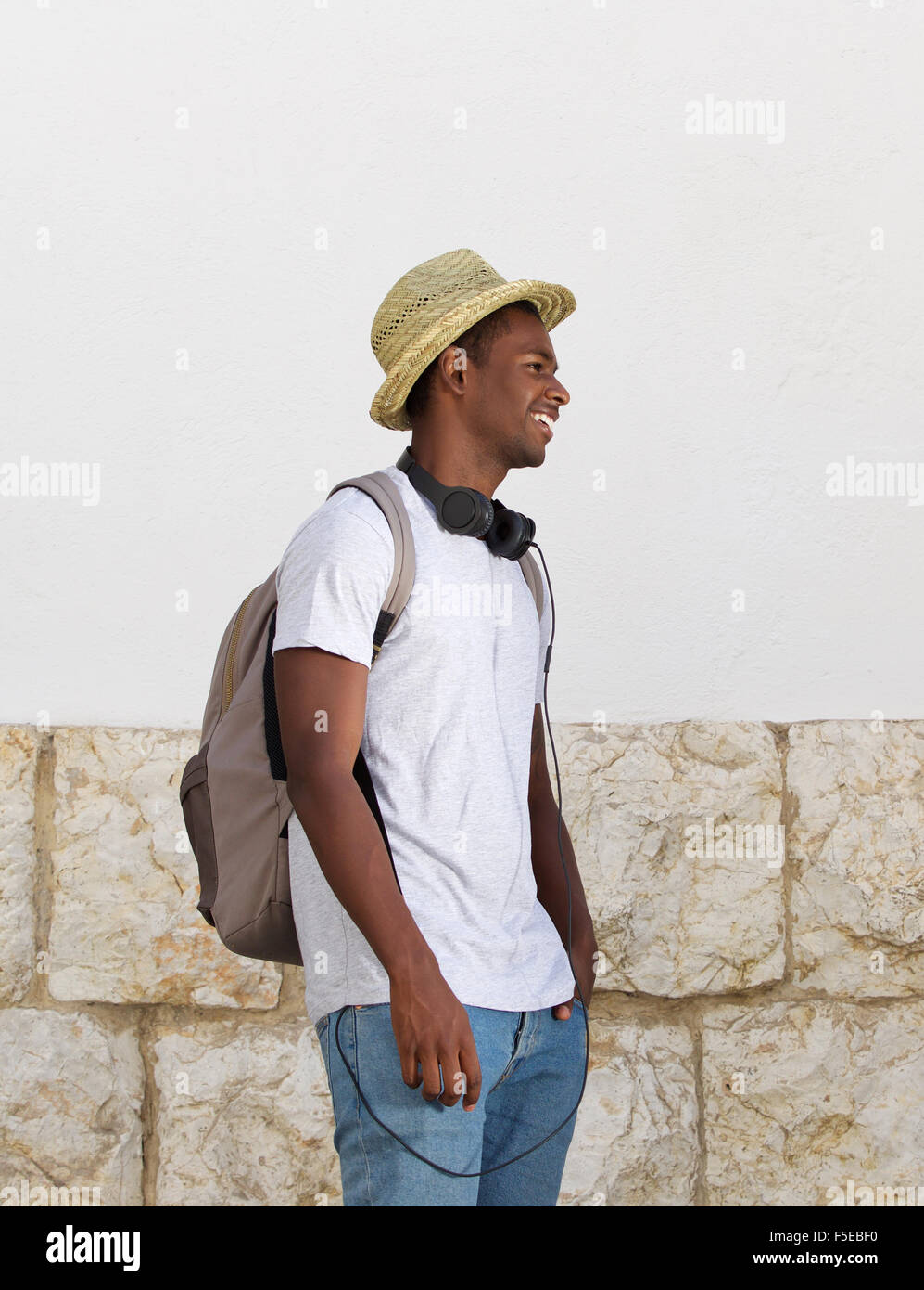 african american student with bag and headphones smiling in front of a ...