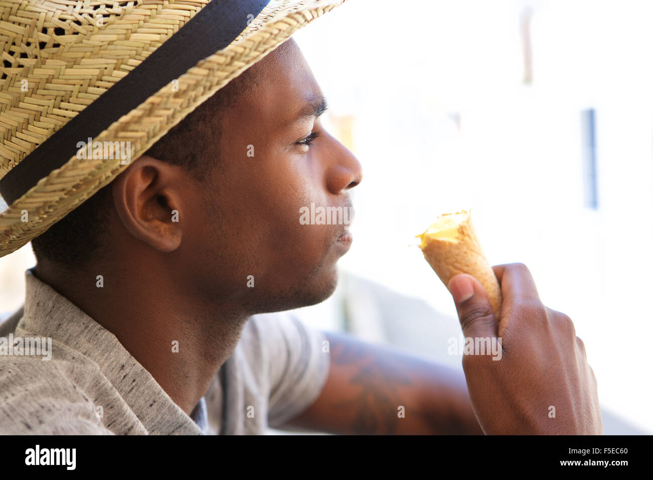 Close up portrait of a young guy with hat eating ice cream Stock Photo