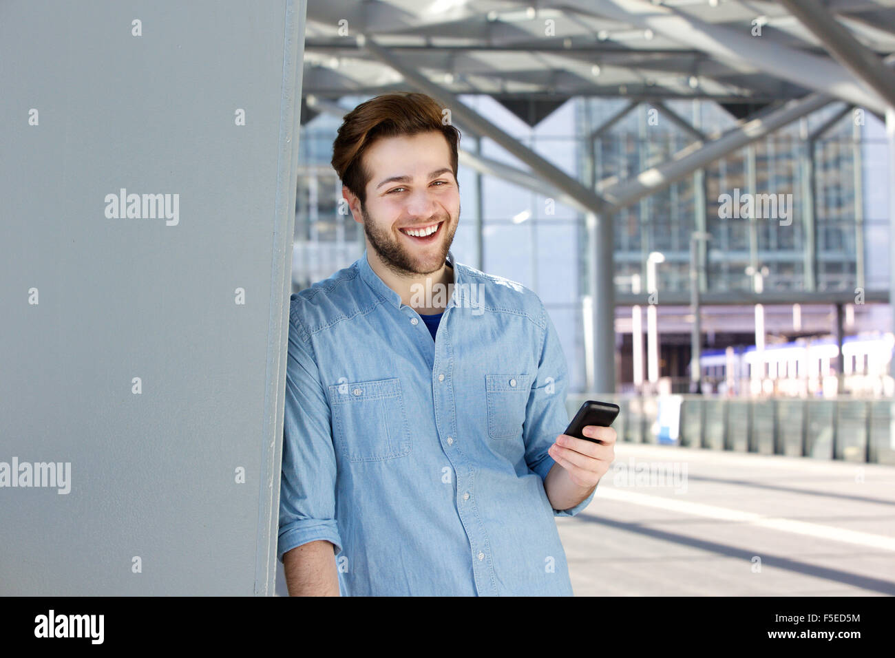 Close up portrait of a happy young man holding mobile phone Stock Photo ...
