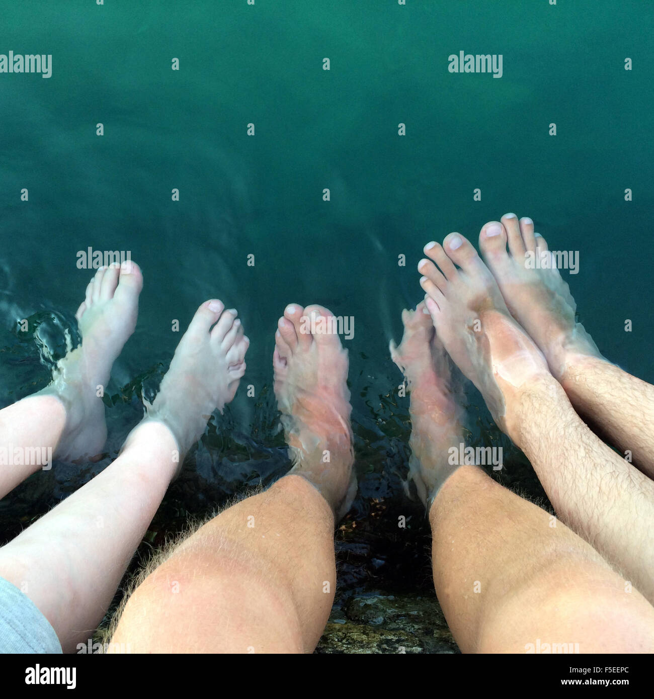 Three men with their feet in water Stock Photo
