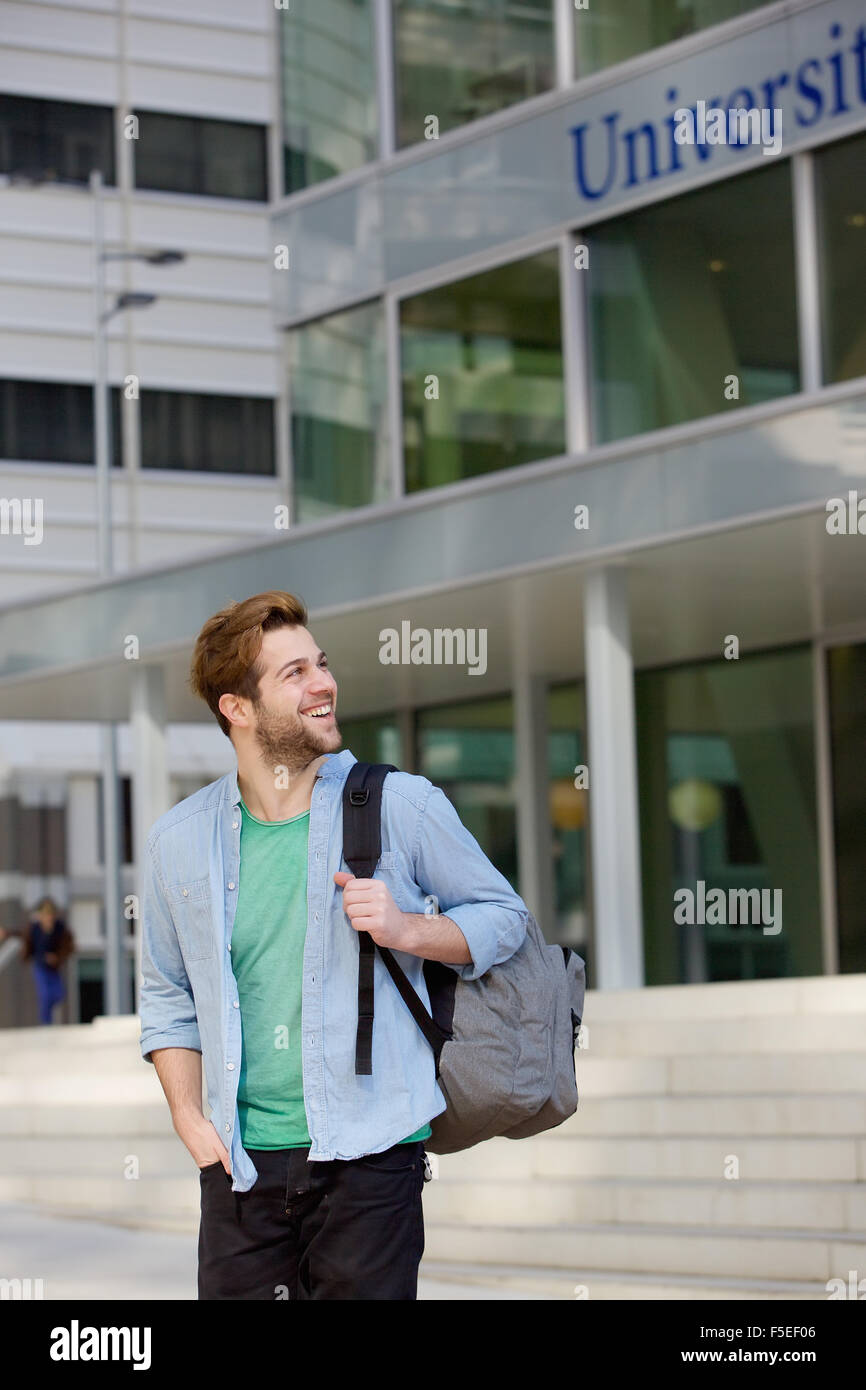 Portrait of a happy male student standing on campus with bag Stock ...