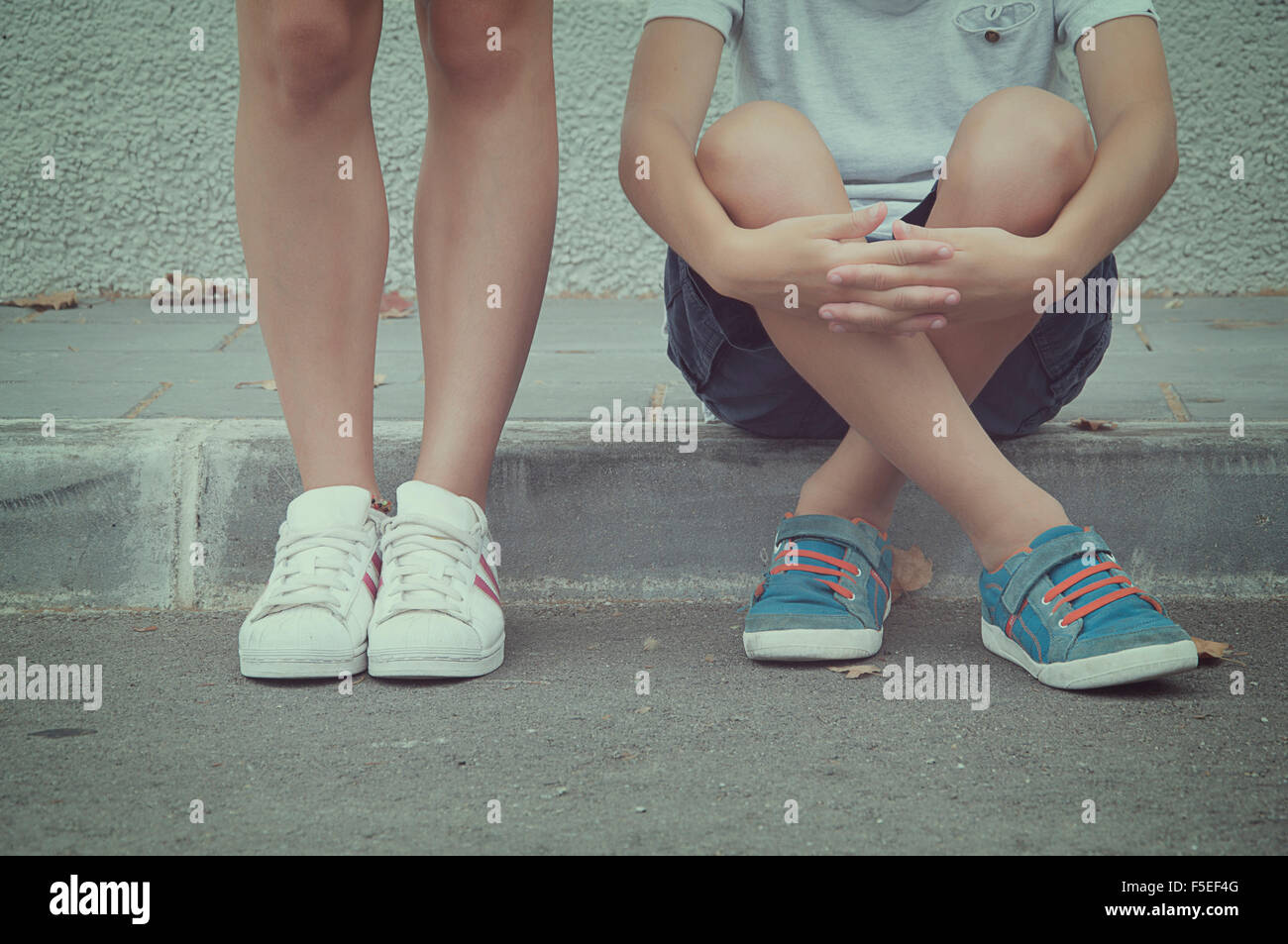 Close-up of two teenagers sitting and standing in the street Stock Photo