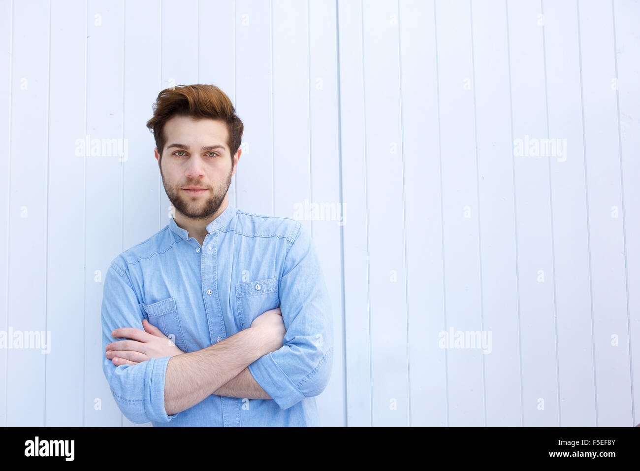 Portrait of a serious young modern man standing with arms crossed Stock Photo