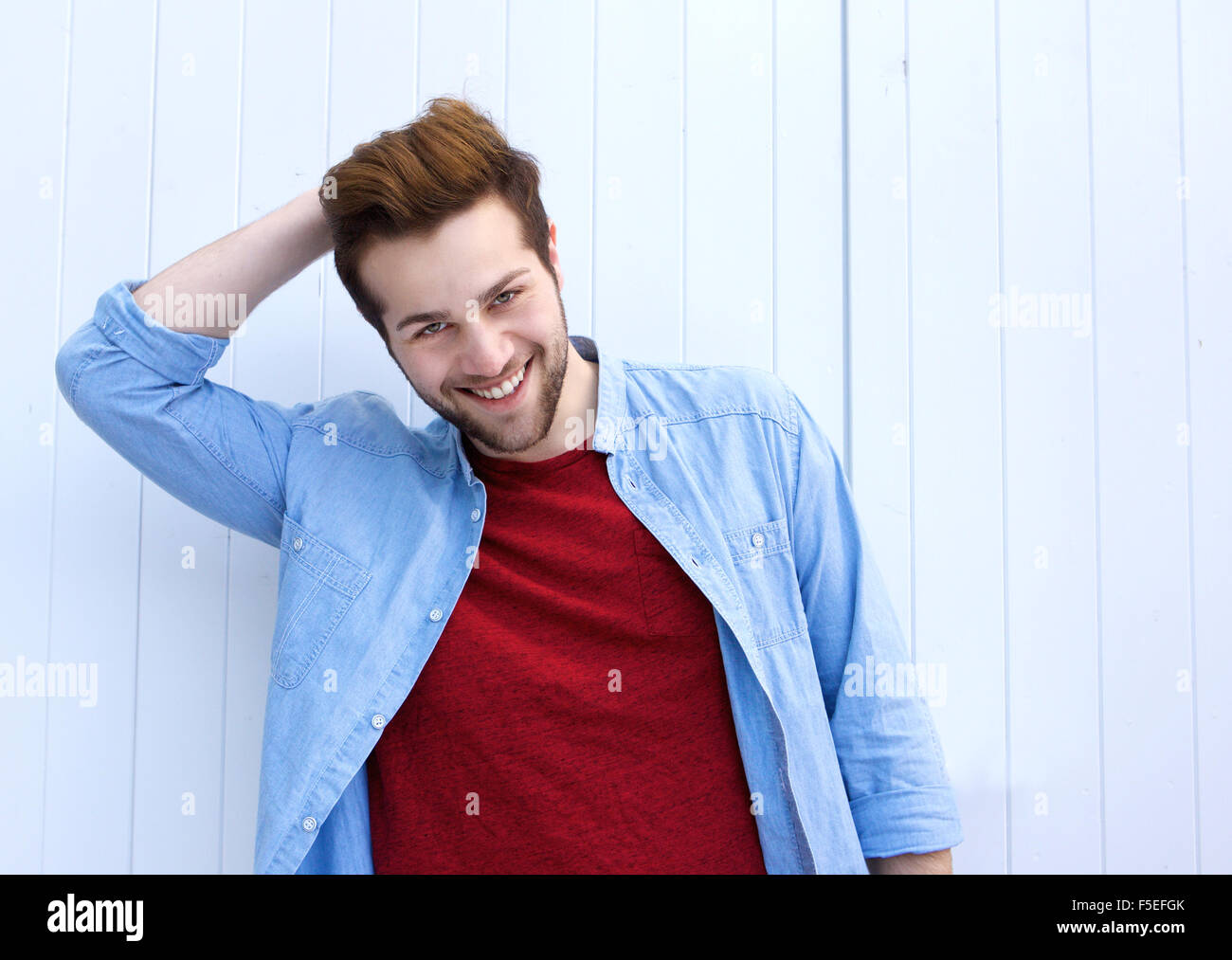 Close up portrait of a handsome young modern man smiling with hand in hair Stock Photo