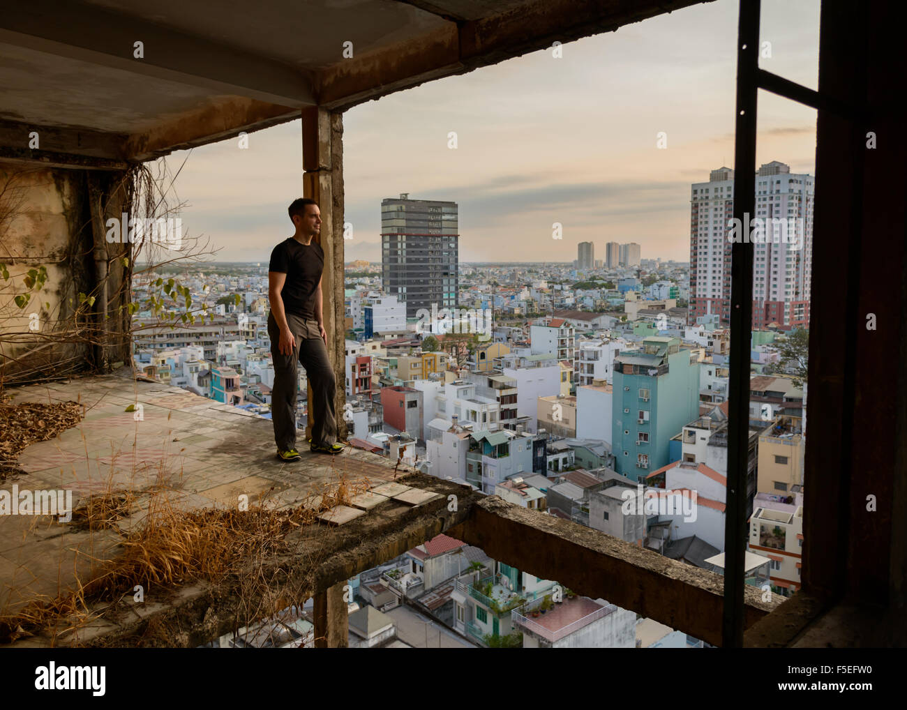 Man standing in derelict building looking at city, Ho Chi Minh, Vietnam Stock Photo