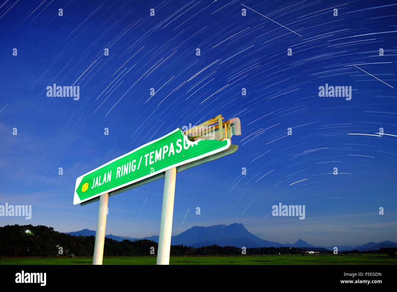 Star trails and broken road sign, Borneo, Malaysia Stock Photo