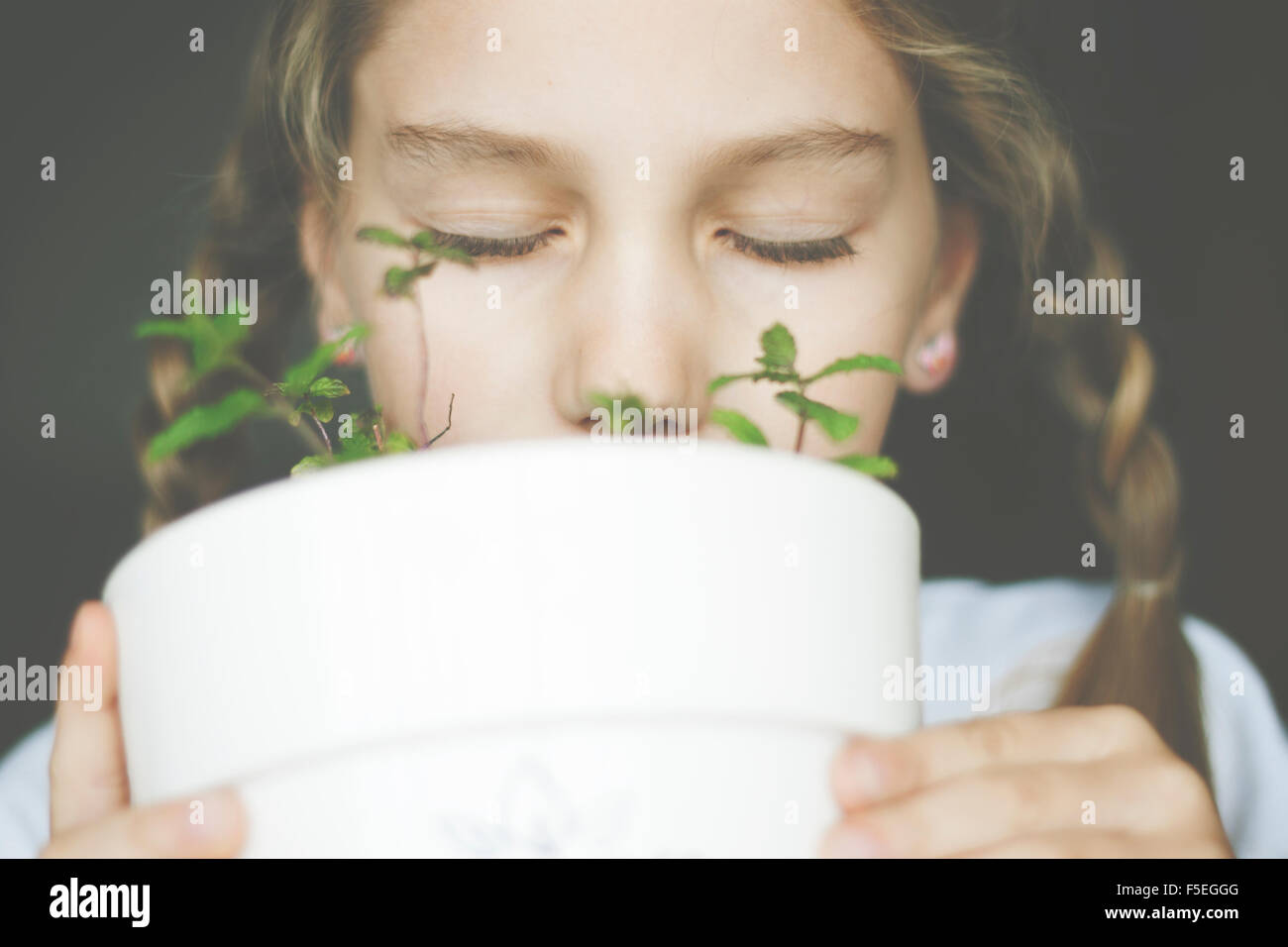Girl smelling mint plant in a plant pot Stock Photo