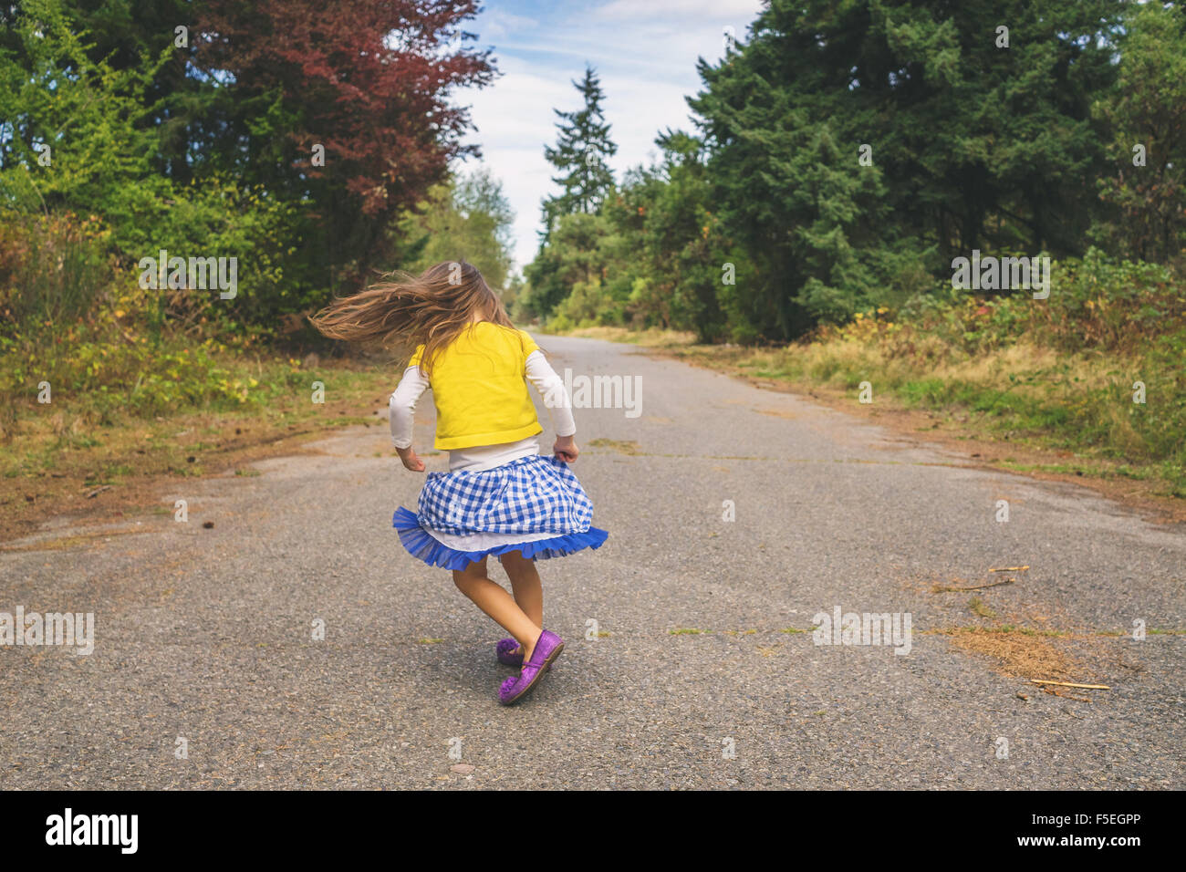 Girl spinning around on a road Stock Photo