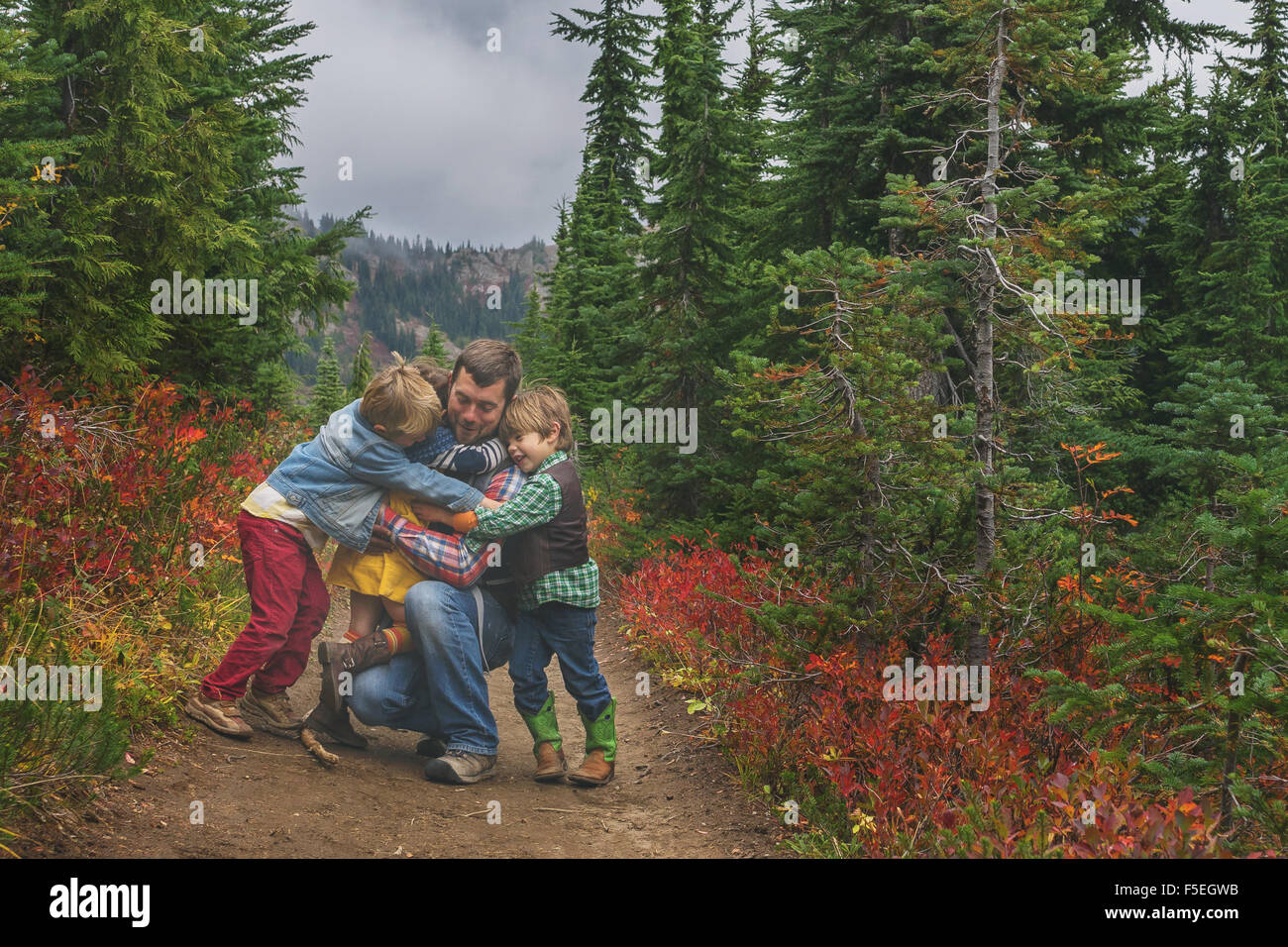 Three children hugging their father Stock Photo