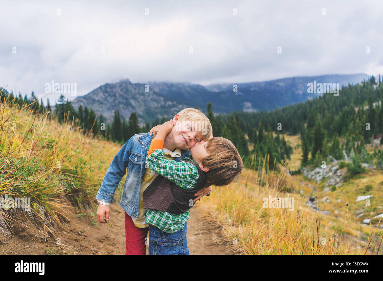 Two brothers hugging and kissing on mountain path Stock Photo