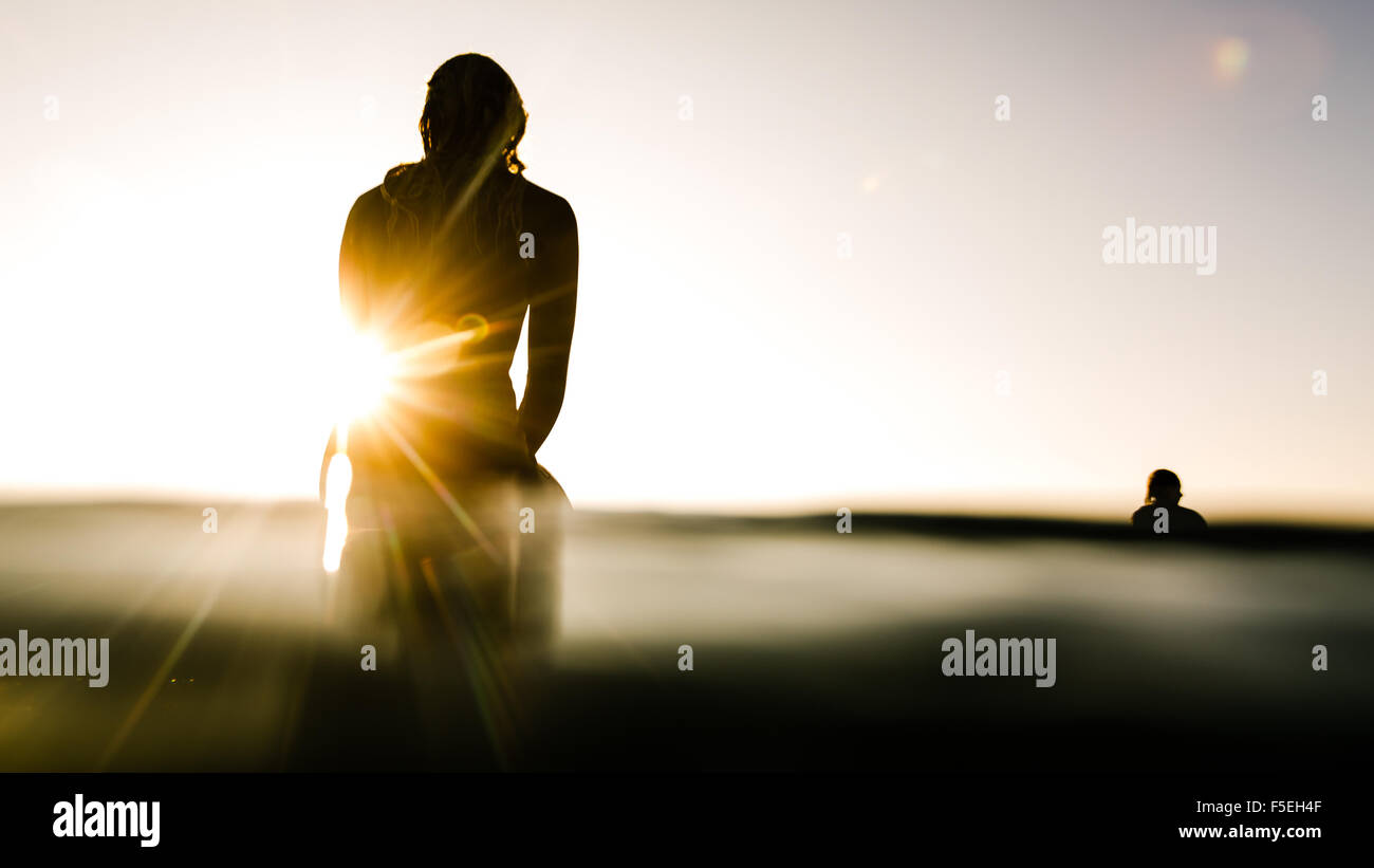 Silhouette of two surfers at sunrise Stock Photo
