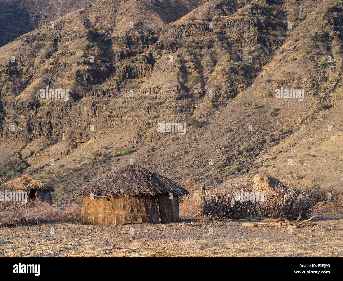 Traditonal round house in a Maasai village in front of the Ol Doinyo Lengai in Arusha Region in Tanzania, Africa, at sunrise. Stock Photo
