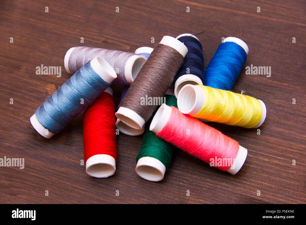 Sewing thread in different colors on wooden table Stock Photo
