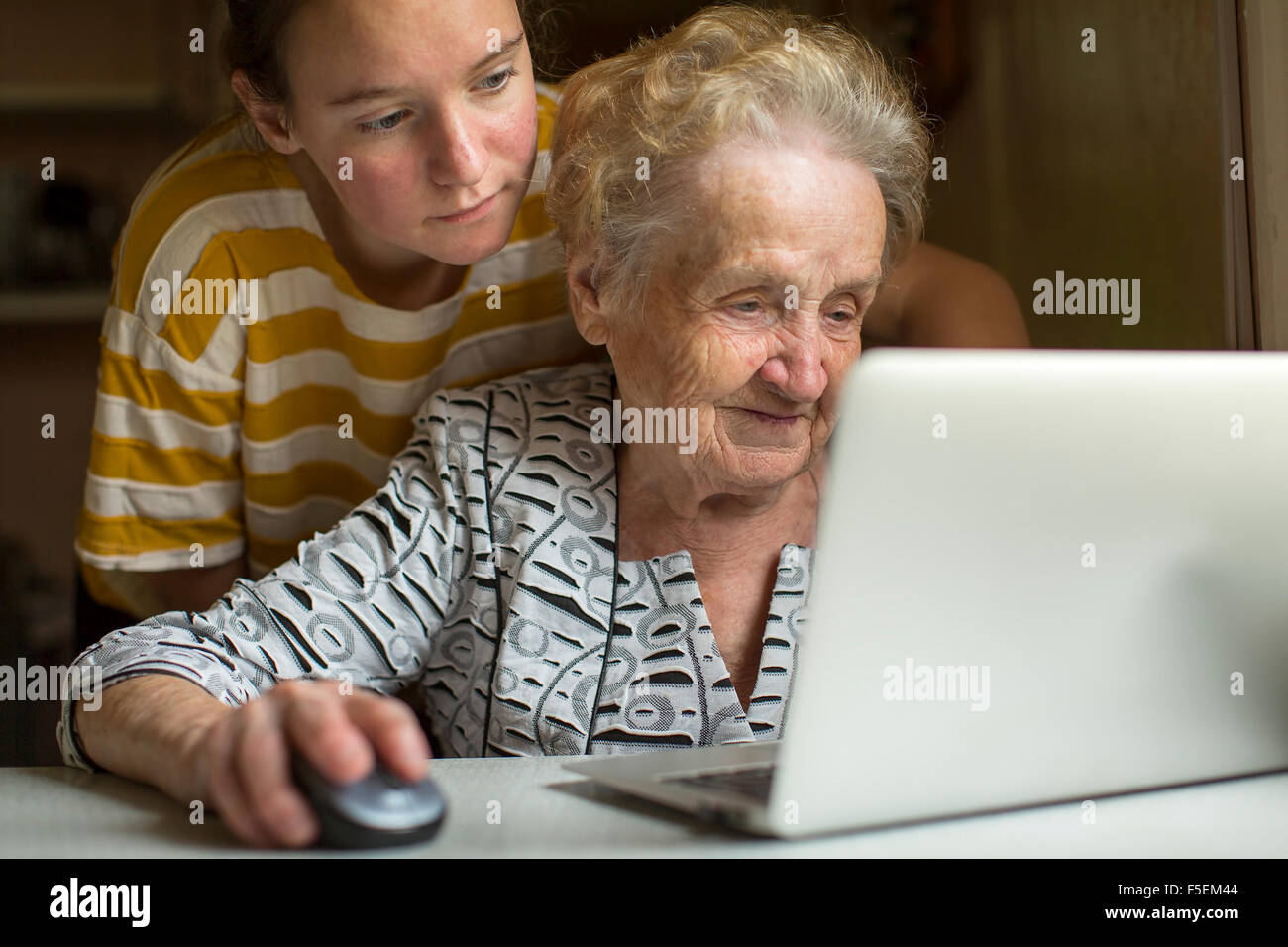 Elderly woman working on laptop with the help of his granddaughter. Stock Photo