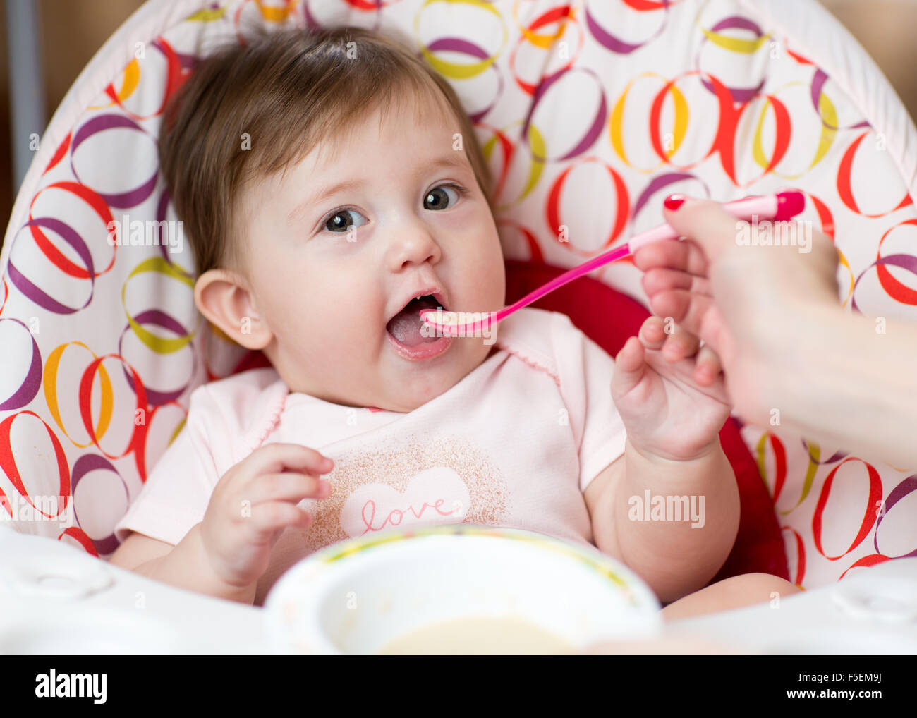 baby kid girl eating food with mother help Stock Photo