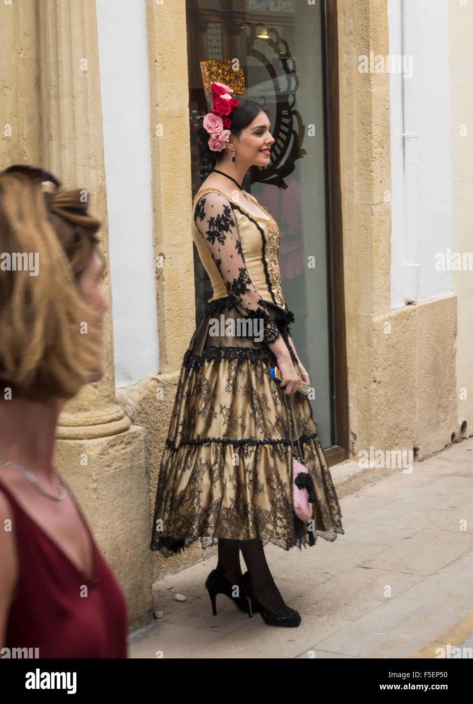 Tourist watches woman in traditional Andalucian dress in Ronda, Spain Stock Photo