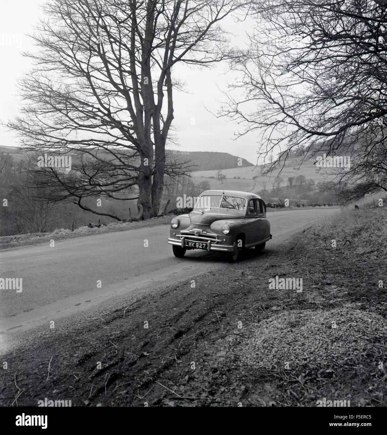 1950s historical picture of a Standard Vanguard car parked on the side of a country road. Stock Photo