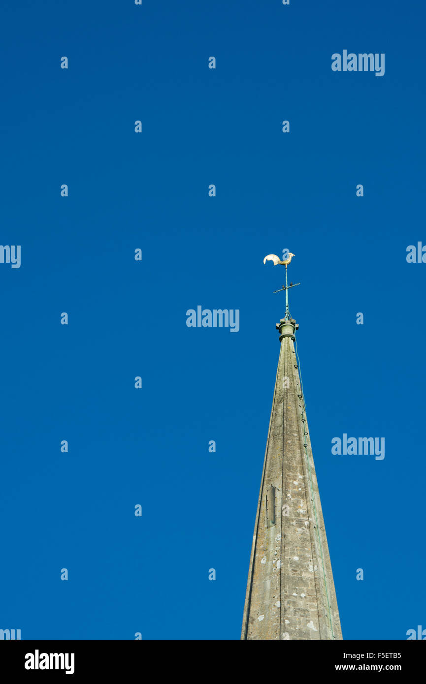 Church spire an cockerel weather vane against blue sky. Cotswolds, Gloucestershire, England Stock Photo