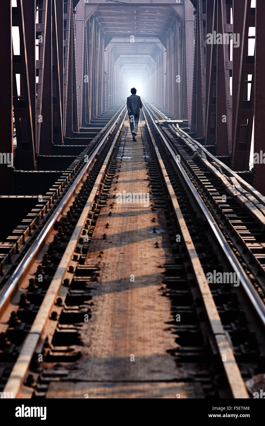 Man walks on railway bridge Stock Photo