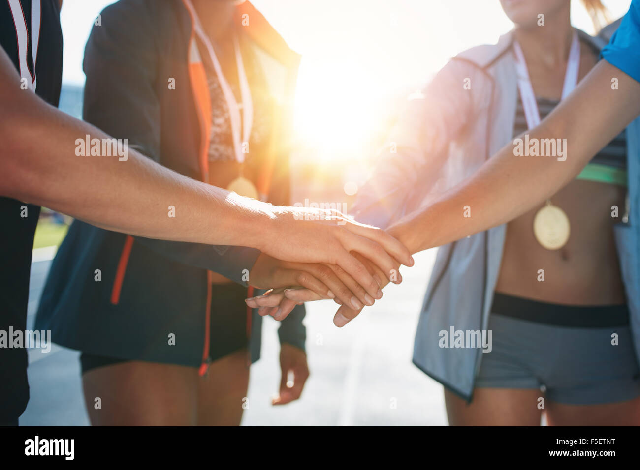 Sports people with hands together in huddle. Team with hands together celebrating success after winning athletics competition. Stock Photo