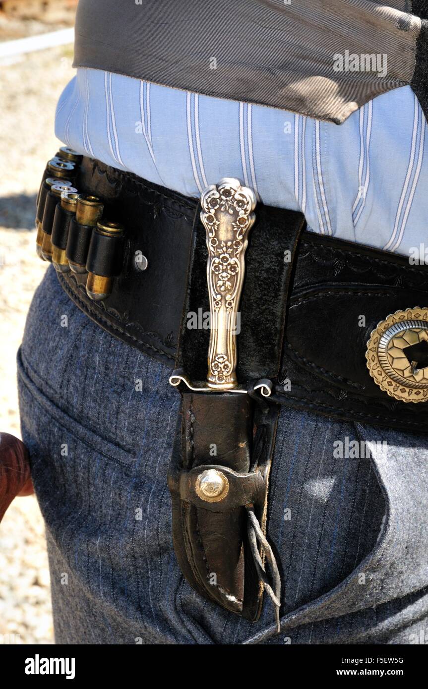 Man wearing a belt holding bullets and a silver handled knife Stock