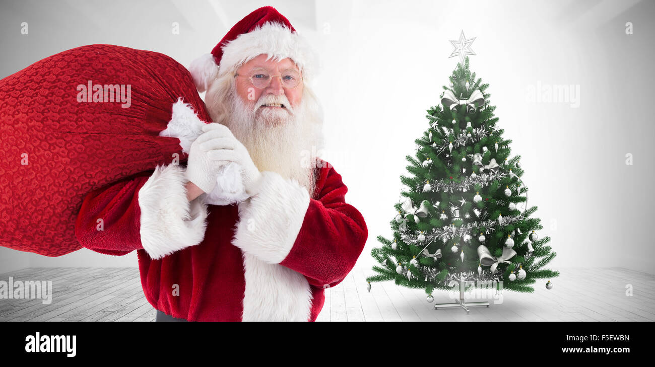 Composite image of santa carries his red bag and smiles Stock Photo - Alamy