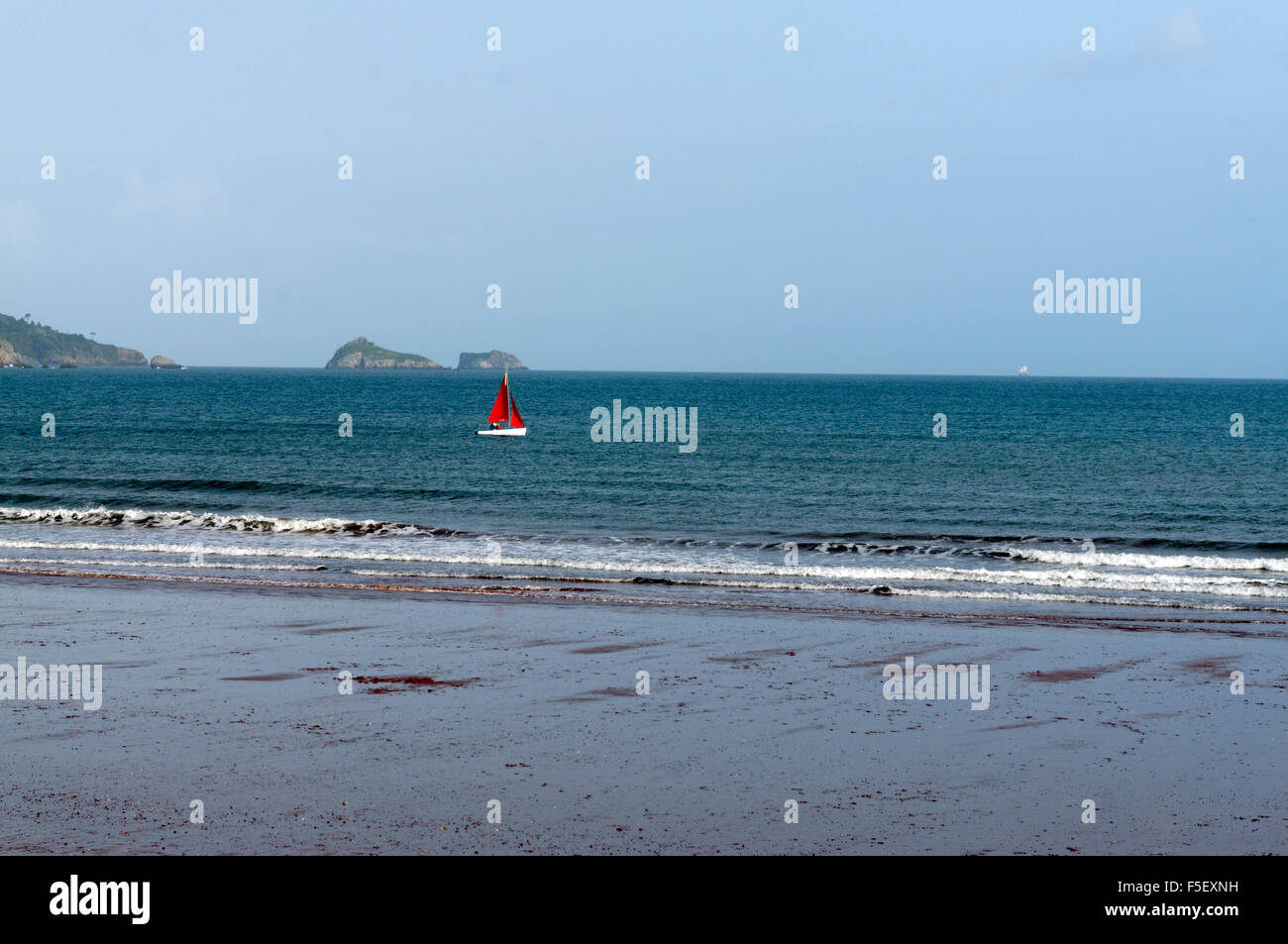 Dinghy with red sail, Preston Sands, Paignton, Tor Bay, Devon, England