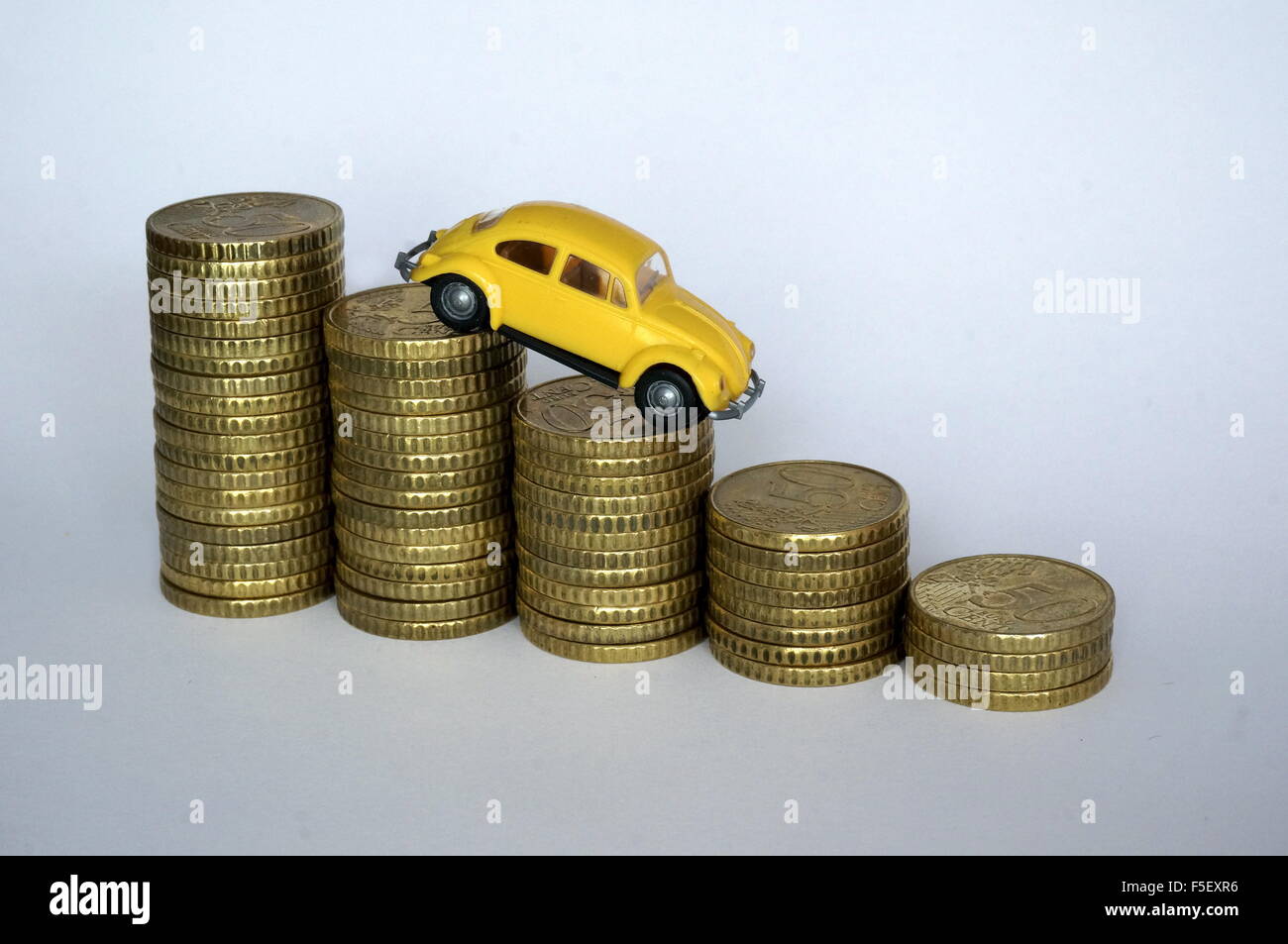ILLUSTRATION - A Volkswagen Beetle model on decreasing money piles. The photo was taken on 06 October 2015. Photo: S. Steinach - NO WIRE SERVICE- Stock Photo