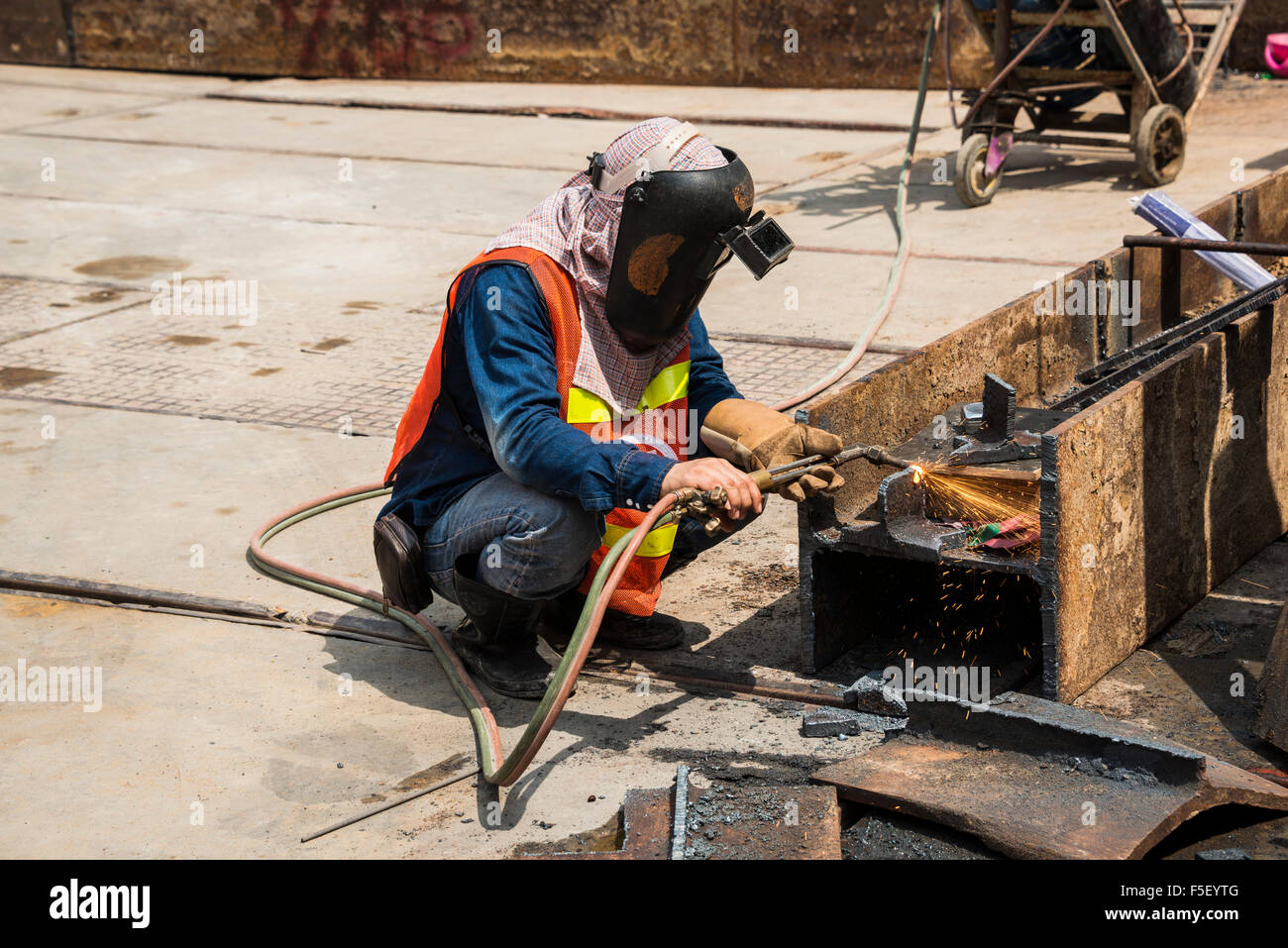 Worker welding steel beam on construction site, Bangkok, Thailand Stock Photo