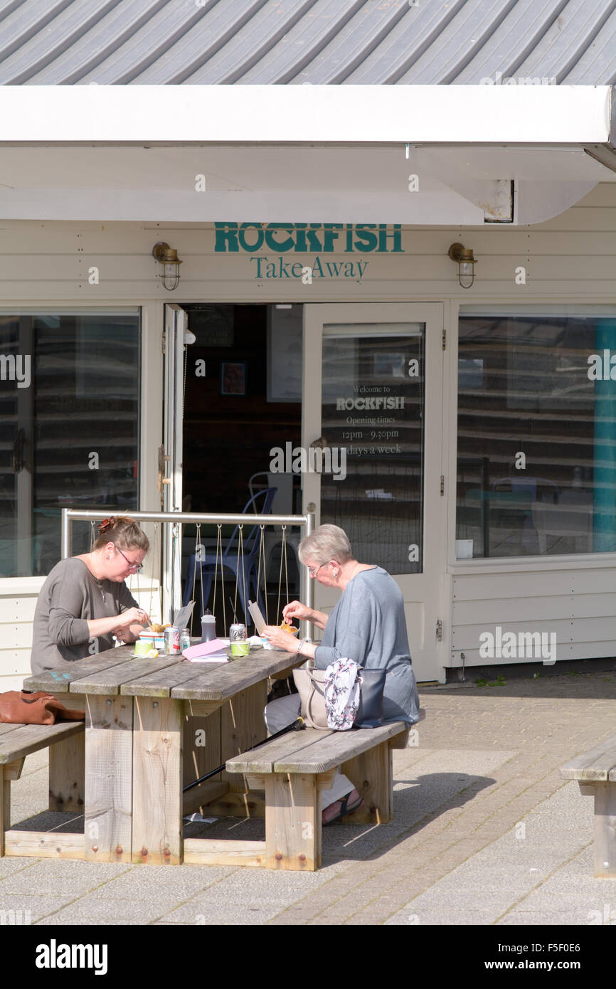 Two women eating fish and chips on the terrace of the Rockfish restaurant in Sutton Harbour, Plymouth, Devon, England Stock Photo