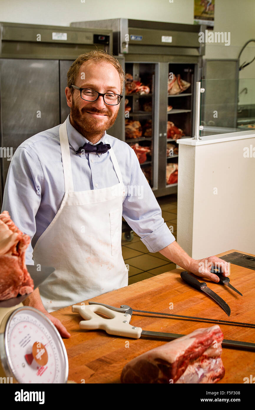 A butcher standing in front of a butchers block with several of his tools Stock Photo