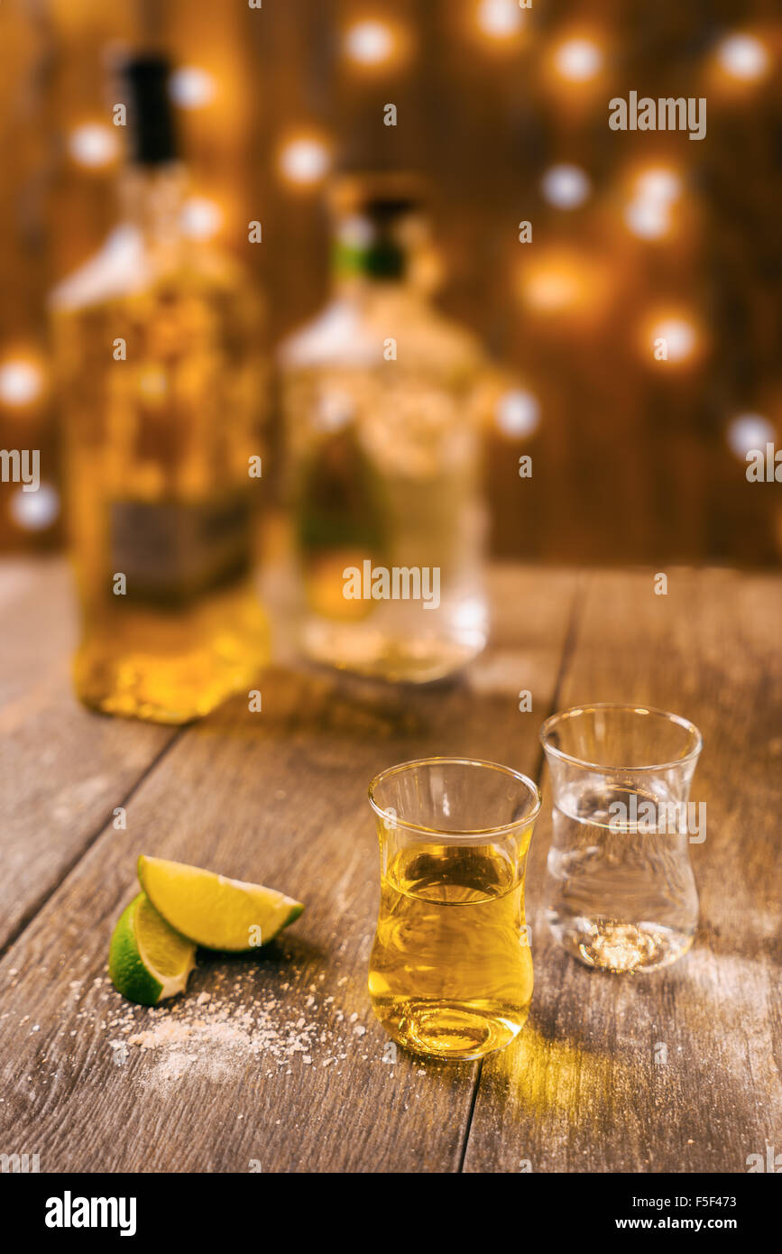 Two shots glasses sitting with lime and salt on a wooden table Stock Photo