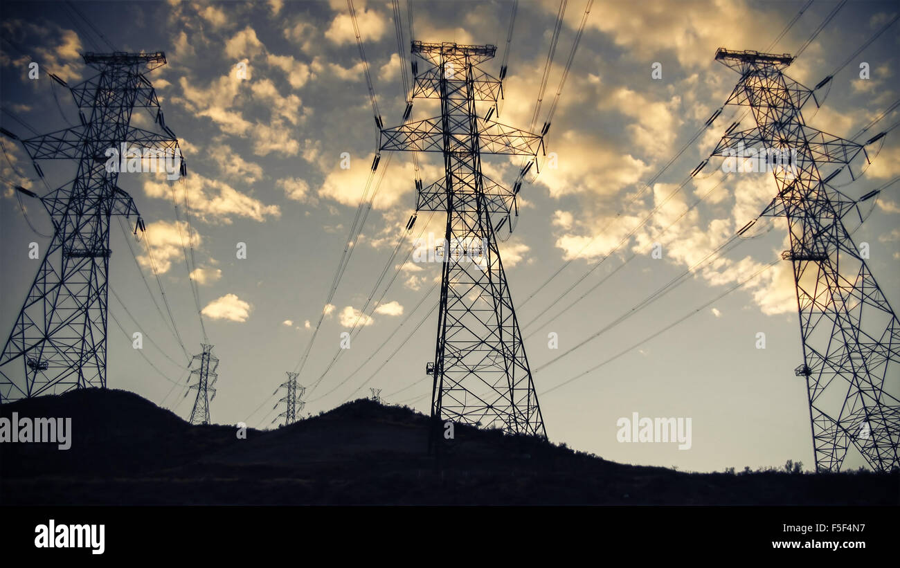 High voltage power lines and towers in silhouette against sunset sky ...