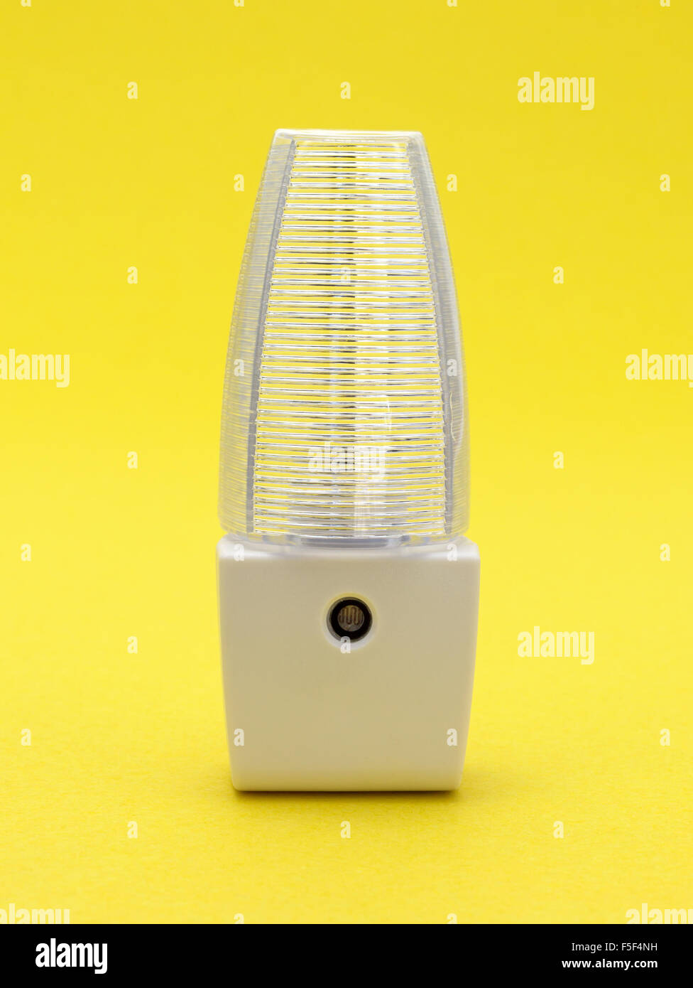 A new generic LED night light that turns on automatically in darkness on a yellow background. Stock Photo