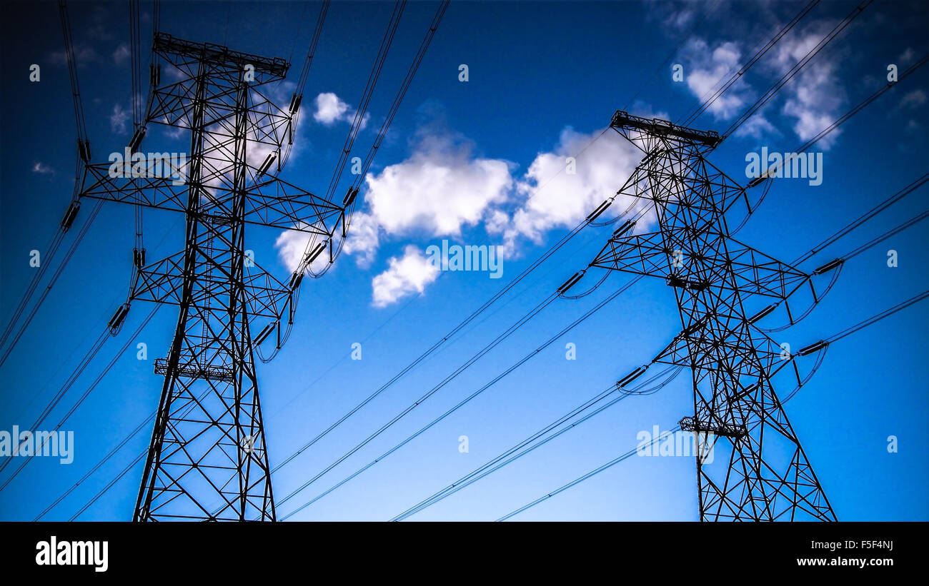 High voltage power lines and towers in silhouette against sunset sky ...