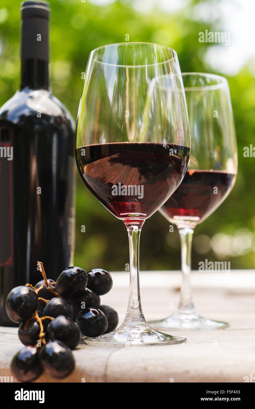 Two wine glasses and a bunch of grapes in front of a wine bottle Stock Photo
